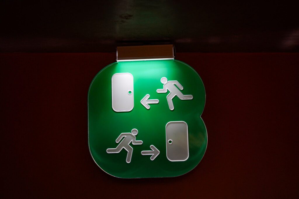 Cartel luminoso de salida colgado sobre una puerta en un pasillo interior