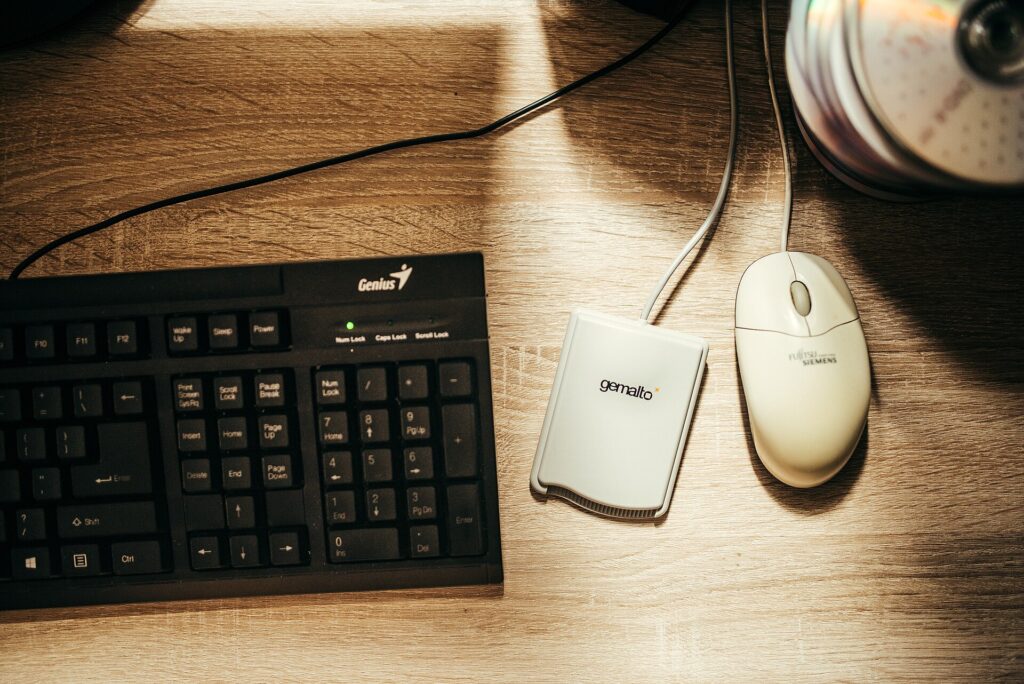 Teclado de ordenador y rat&oacute;n sobre un escritorio despejado con una libreta al lado