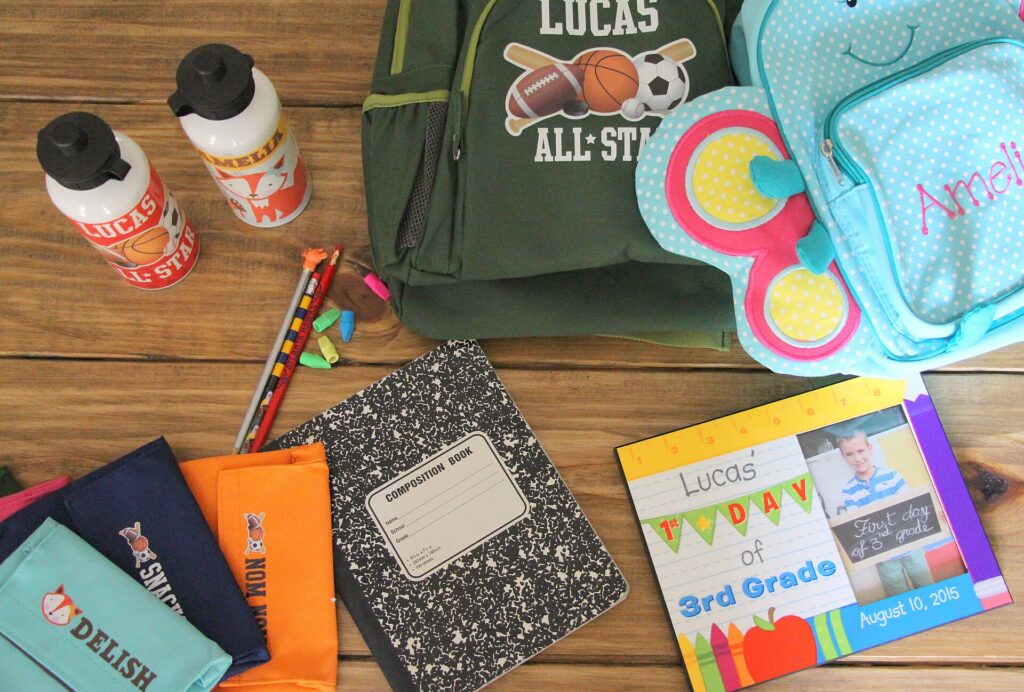Mochila escolar abierta con libros de texto y un estuche apoyada en el suelo