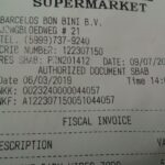 Tique de compra impreso y desplegado sobre una mesa junto a un bolígrafo y unas monedas