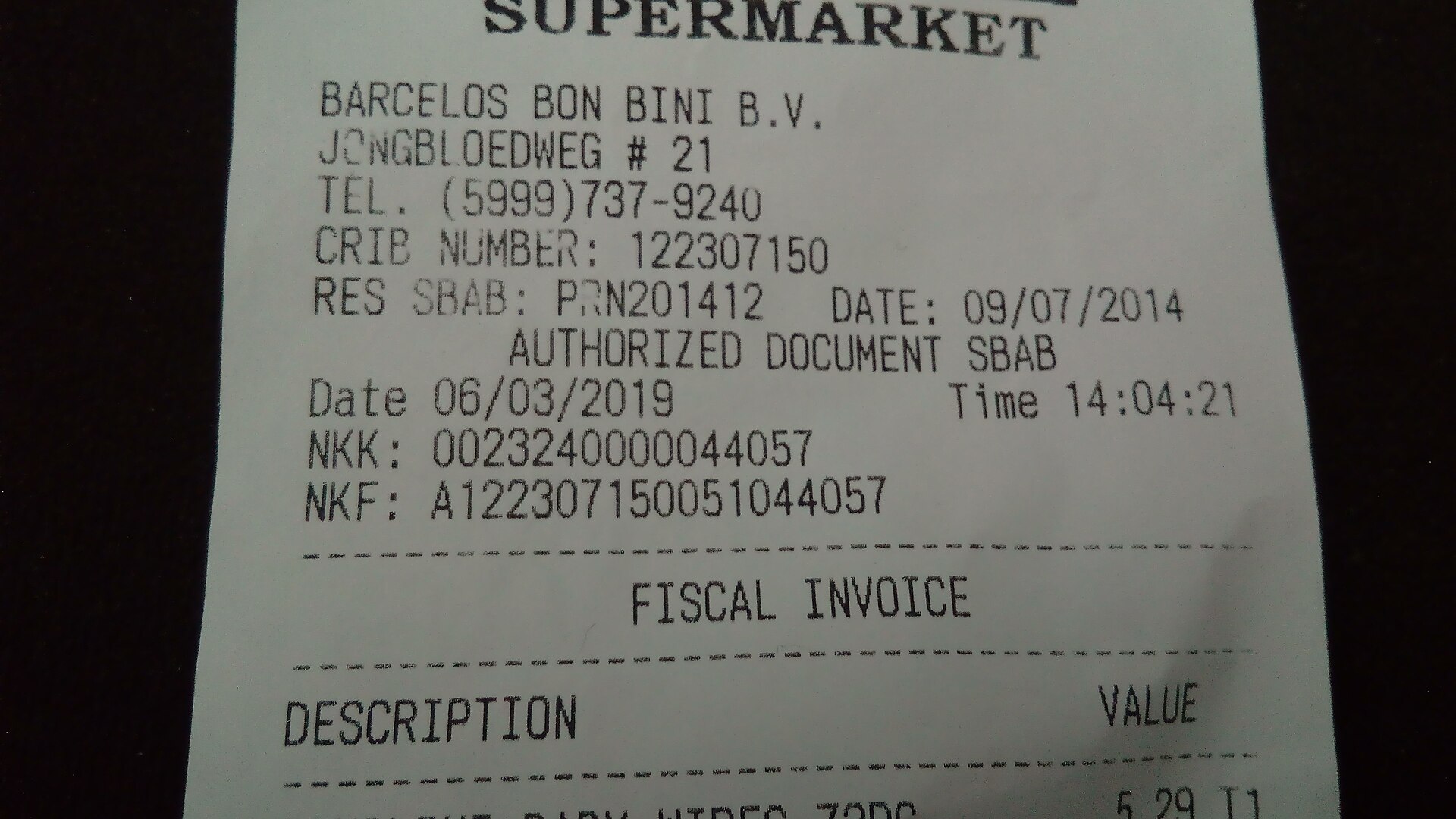 Tique de compra impreso y desplegado sobre una mesa junto a un bolígrafo y unas monedas