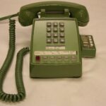 Teléfono fijo de oficina con el auricular descolgado sobre una mesa con papeles