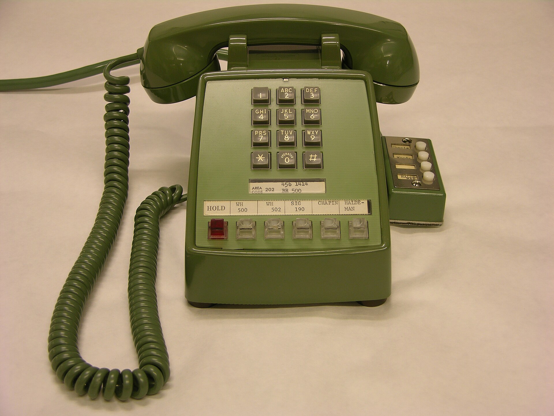 Teléfono fijo de oficina con el auricular descolgado sobre una mesa con papeles