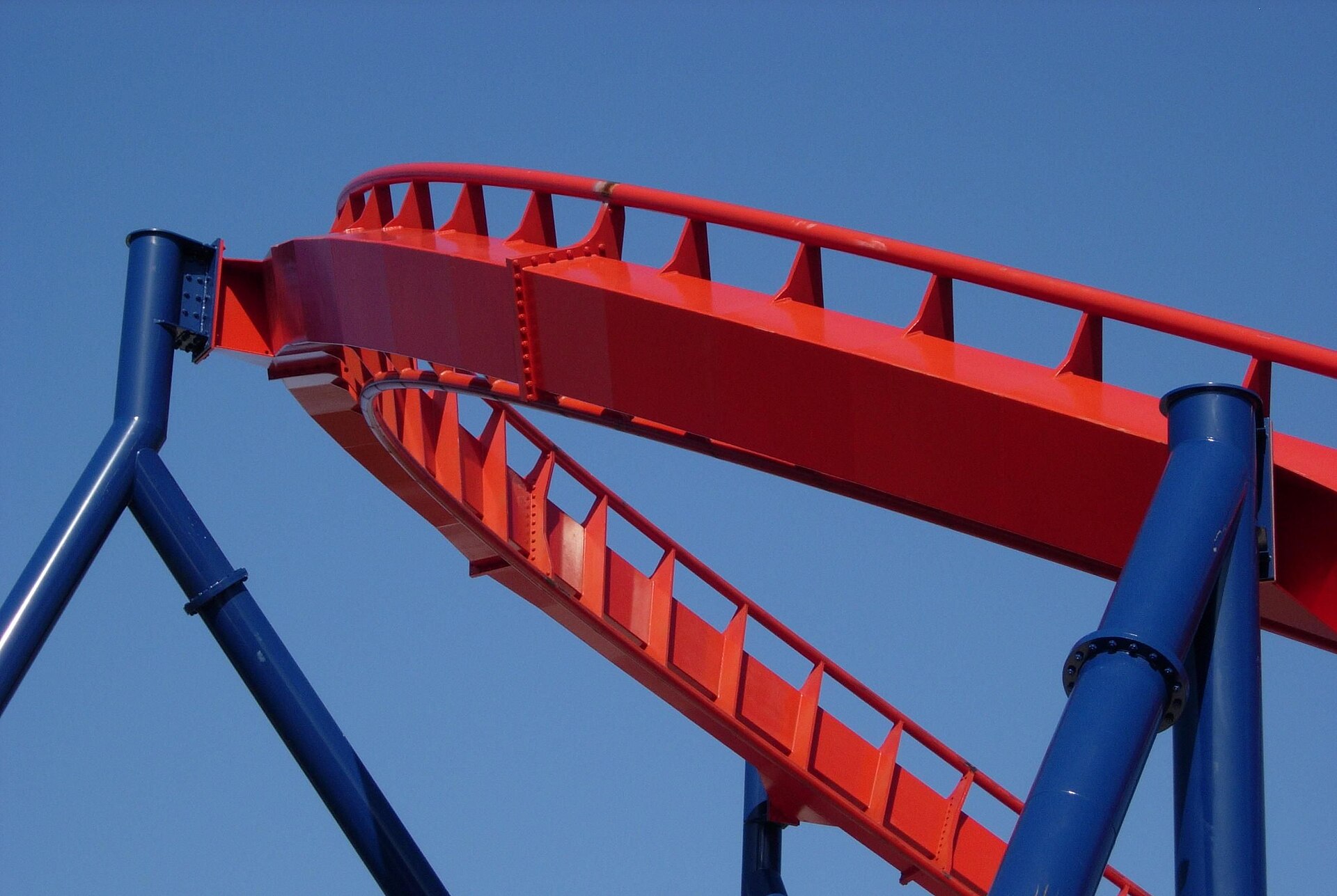 Vía metálica de una montaña rusa con una curva pronunciada recortada contra el cielo