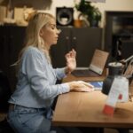 1920px-Woman_sits_at_desk_working_on_laptop_in_home_office