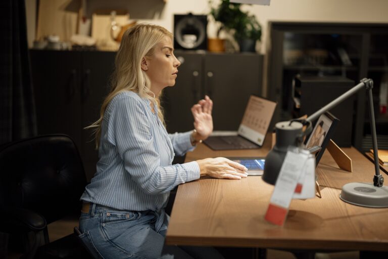 1920px-Woman_sits_at_desk_working_on_laptop_in_home_office