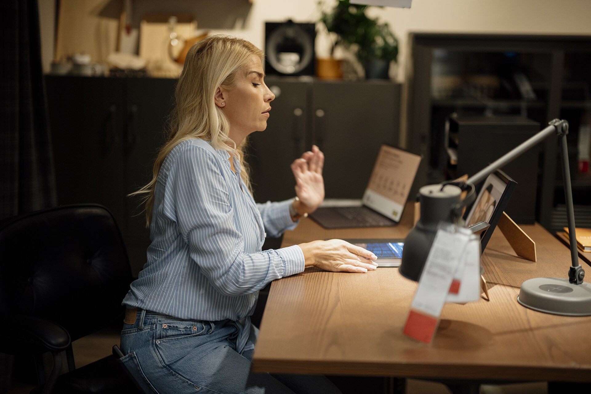 1920px-Woman_sits_at_desk_working_on_laptop_in_home_office