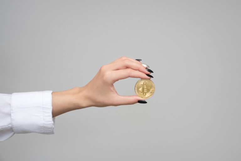 Monedas metálicas apiladas junto a un teclado de ordenador sobre una mesa de madera oscura
