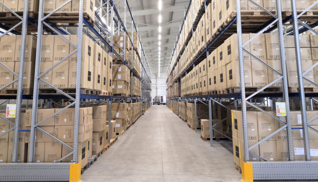 Estanterías metálicas de un almacén con palés y cajas apiladas hasta el techo