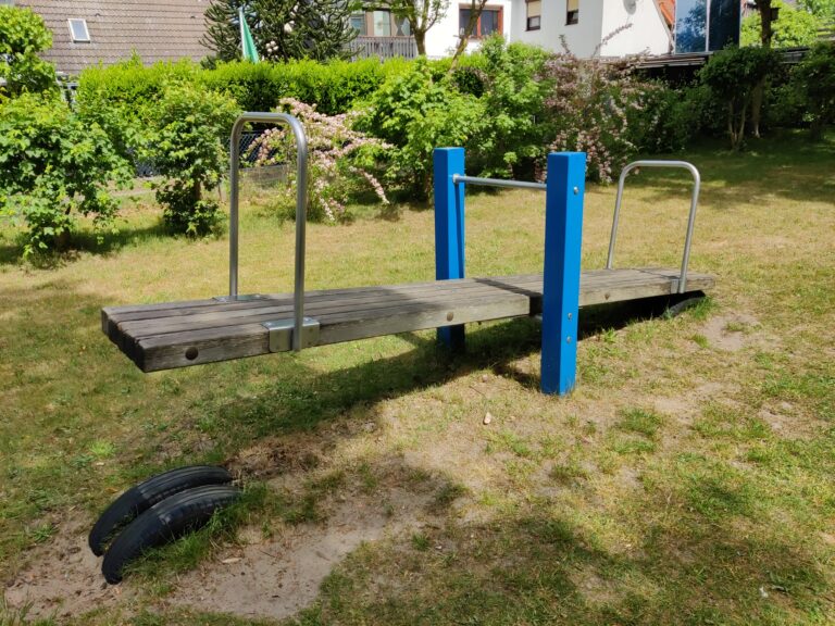 Balancín de madera en un parque infantil vacío, con los dos asientos a distinta altura