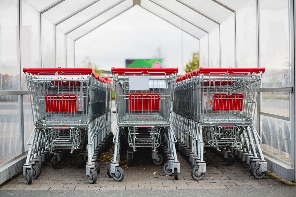 Carro de la compra medio lleno en el pasillo de un supermercado con estanterías a los lados
