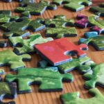 Piezas de un rompecabezas de cartón esparcidas sobre una mesa, algunas ya encajadas