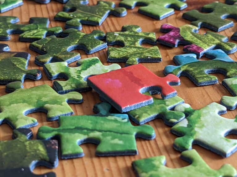 Piezas de un rompecabezas de cartón esparcidas sobre una mesa, algunas ya encajadas