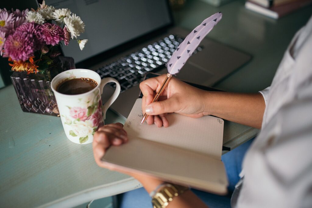 Cuaderno con anotaciones, un bolígrafo y una taza de café sobre un escritorio de trabajo