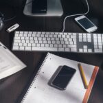 Cuaderno abierto con anotaciones a mano y una calculadora sobre una mesa de madera clara