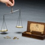 Balanza antigua de latón con dos platillos y varias pesas colocadas sobre una mesa