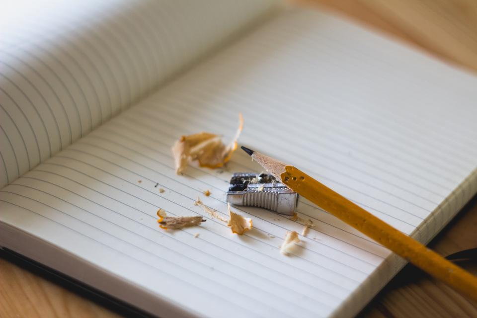 Cuaderno de papel cerrado junto a una caja metálica pequeña sobre un escritorio