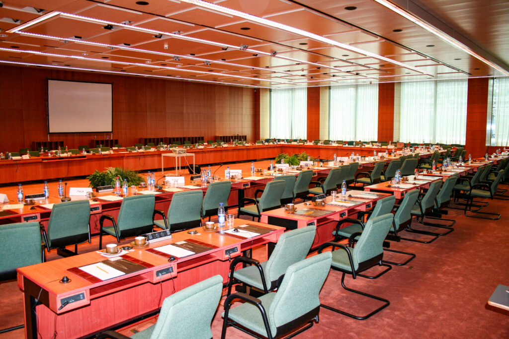 Sala de reuniones con mesa alargada de madera y sillas vacías junto a una ventana