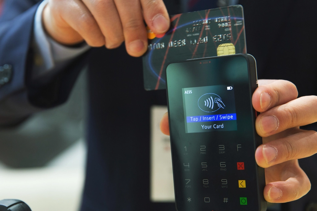 Terminal de pago con una tarjeta insertada sobre el mostrador de un peque&ntilde;o negocio